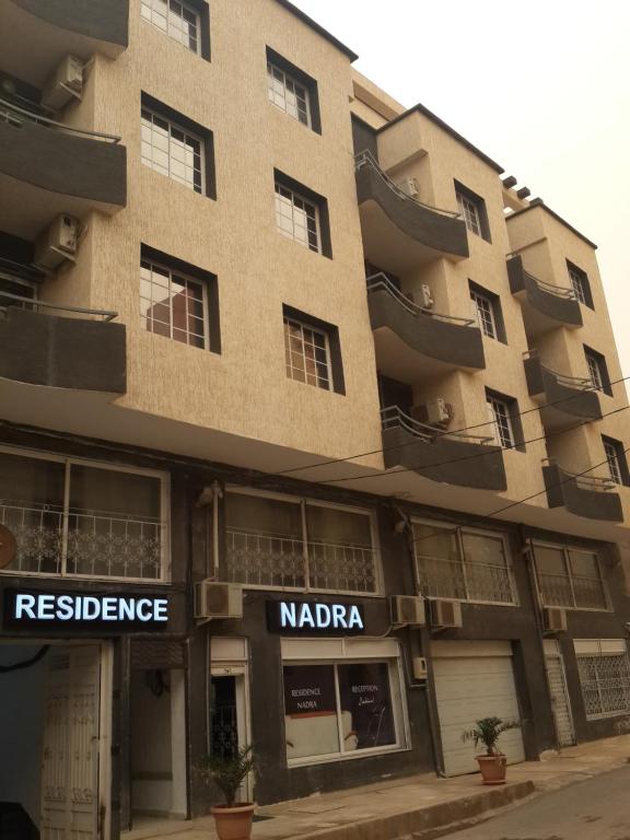 an apartment building with a sign for a restaurant at Residence Nadra in 'Aïn el Turk