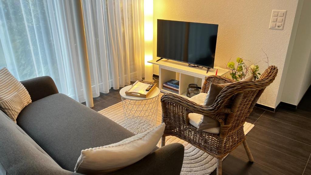 a living room with a couch and chairs and a television at Modern apartment Pilatus view self check-in in Stans