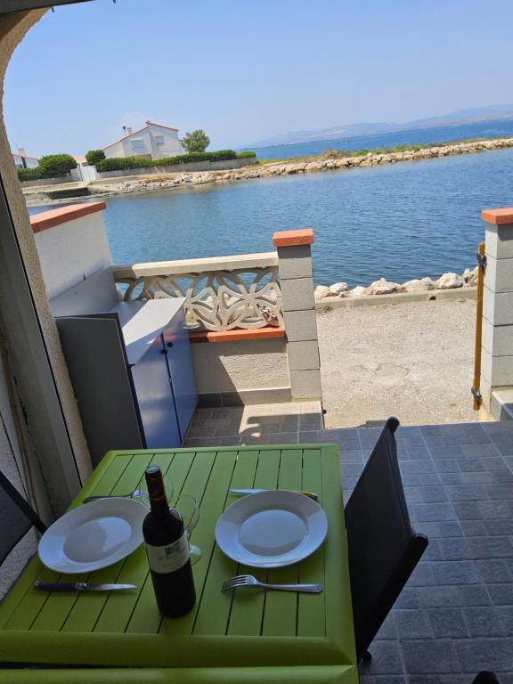 RARE maison du pêcheur en première ligne avec clim في لو باركار: طاولة خضراء مع أطباق وزجاجة من النبيذ