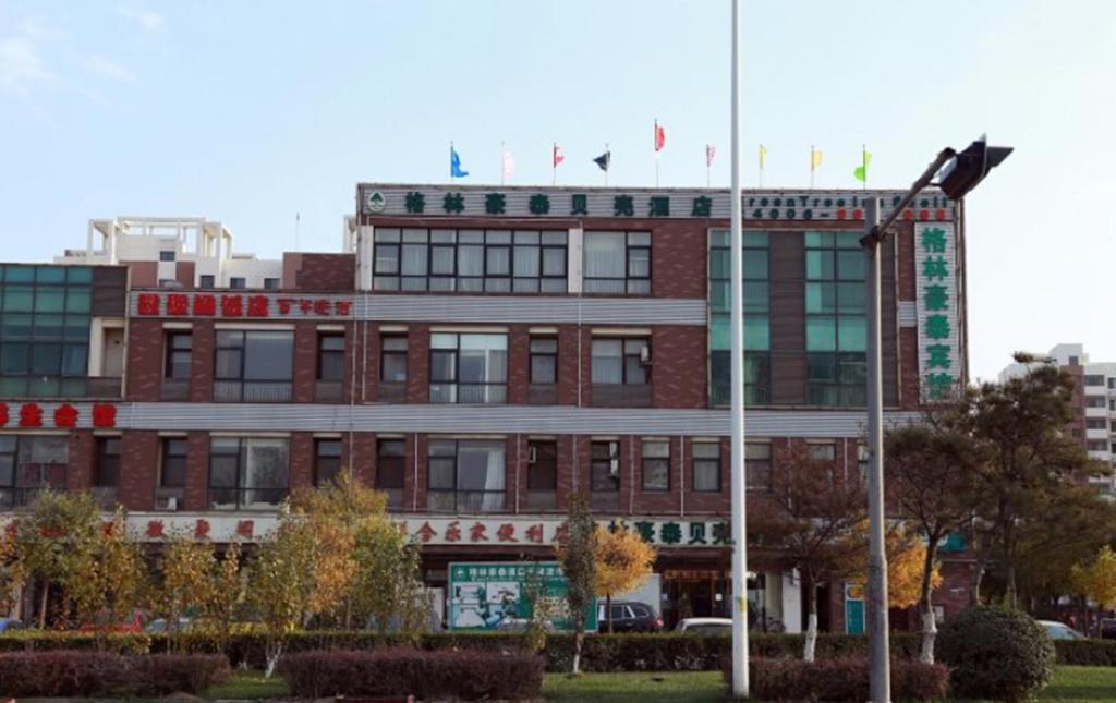 a red brick building with flags on top of it at GreenTree Inn Tianjin Jinnan Shuanggang Lishuang Road Shell Hotel in Tianjin