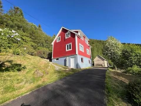 una casa roja y blanca al lado de una carretera en Haus Harald, en Tysnes