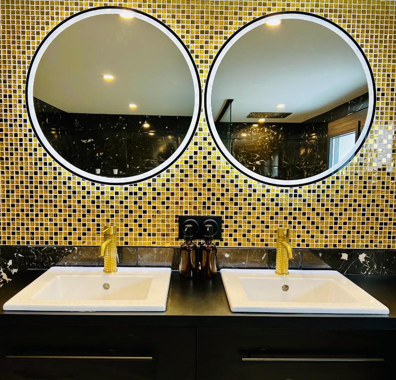two sinks in a bathroom with two mirrors at La Suite Saint Roch in Villeréal