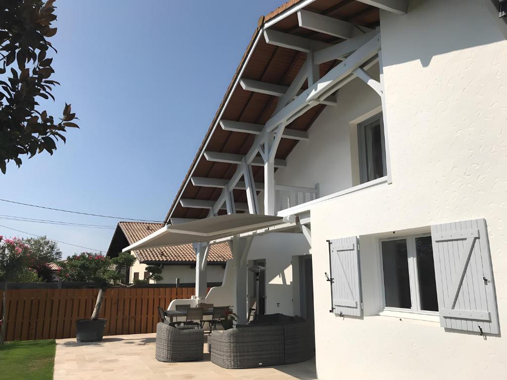 una casa bianca con un patio con tavolo e sedie di Chambre D'hote Chez Amaya a Gujan-Mestras