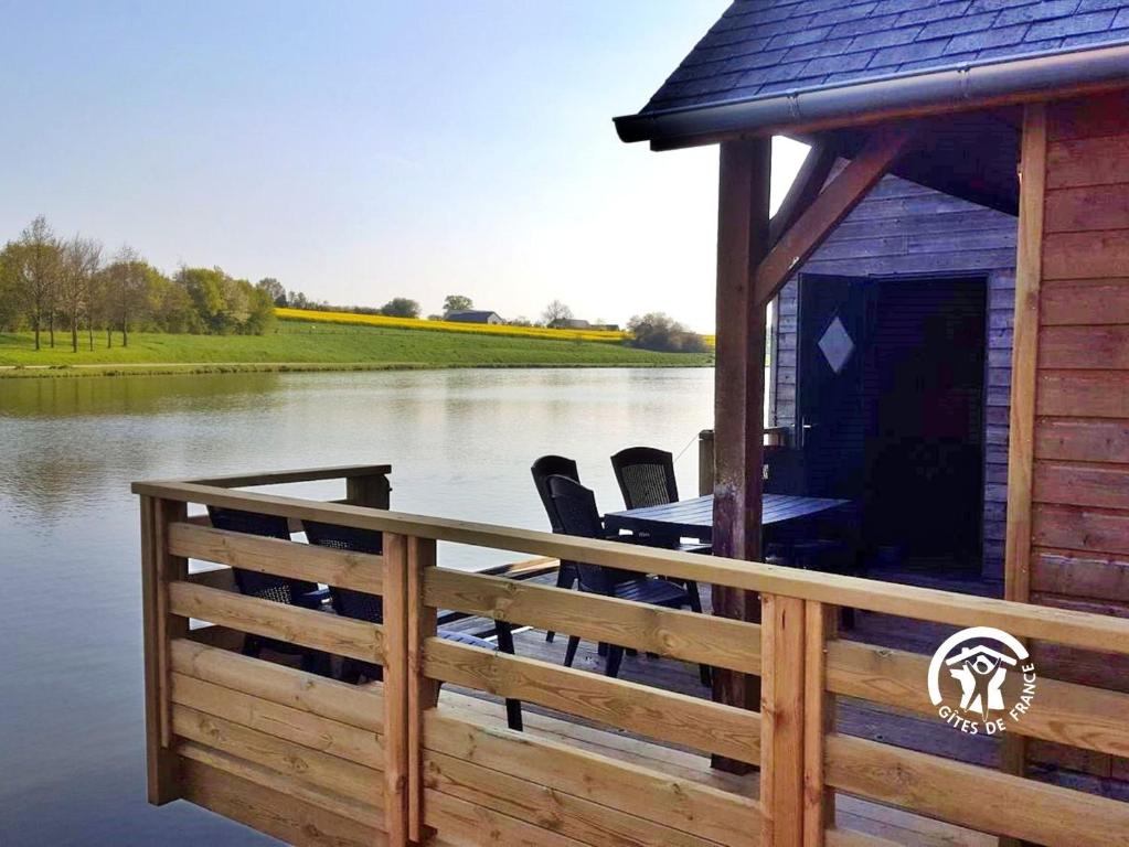 a deck with chairs and a house on a body of water at Chalet la Tanche in Villiers-Charlemagne