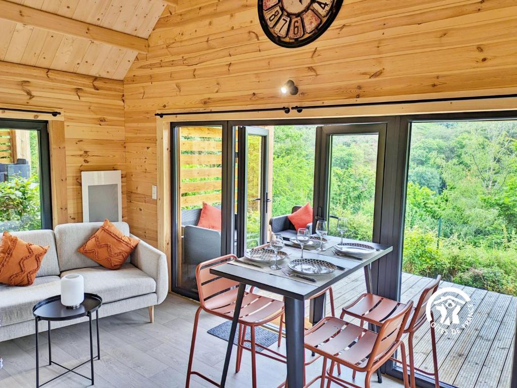 a living room with a table and chairs and a clock at Chalet 24 La Forêt, Camping de Coupeau, 4 personnes in Saint-Berthevin