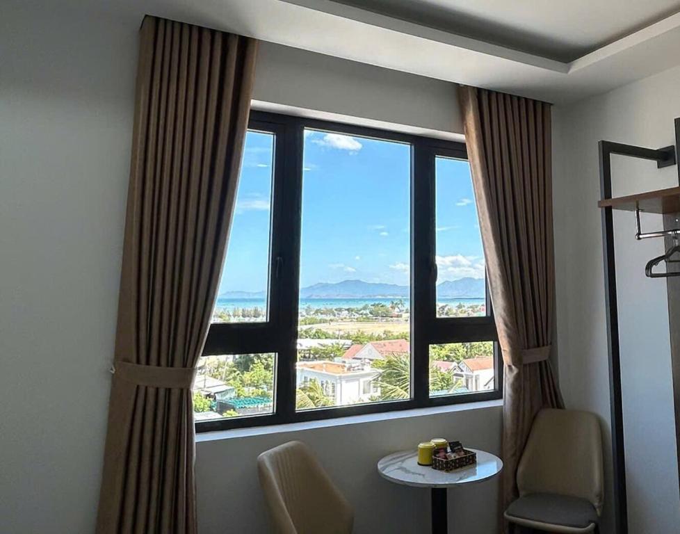 a room with a large window with a table and chairs at Hilaria Hotel in Vạn Ninh