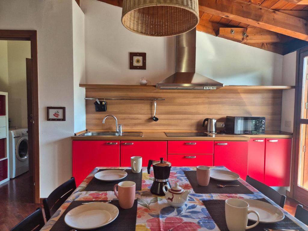 a kitchen with red cabinets and a table with chairs at I Lecci By Case al Lago in Brescia
