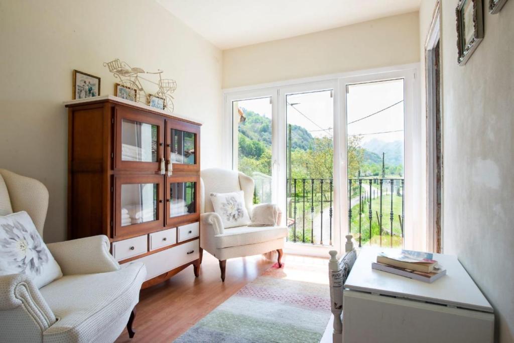 a living room with a chair and a table and a window at La Casa de Ethel en norte de España VV-2427-AS in Cangas de Onís