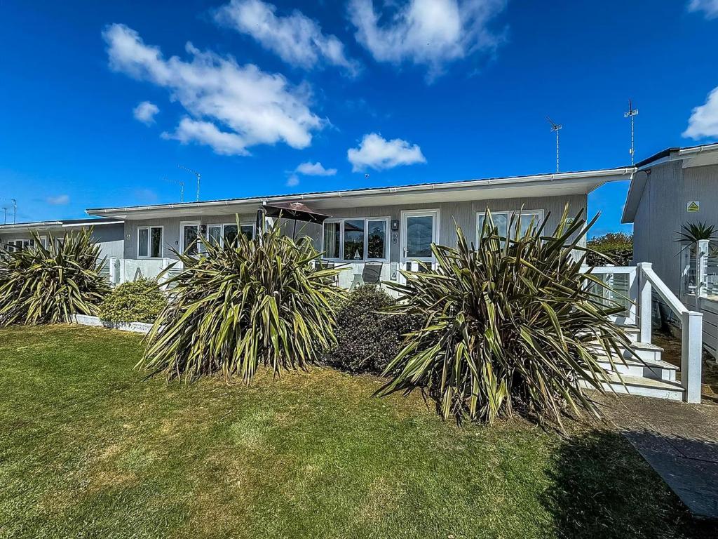 a house with two large plants in front of it at Cosy Chalet On A Beautiful Holiday Park In Lowestoft Ref 12080B in Lowestoft