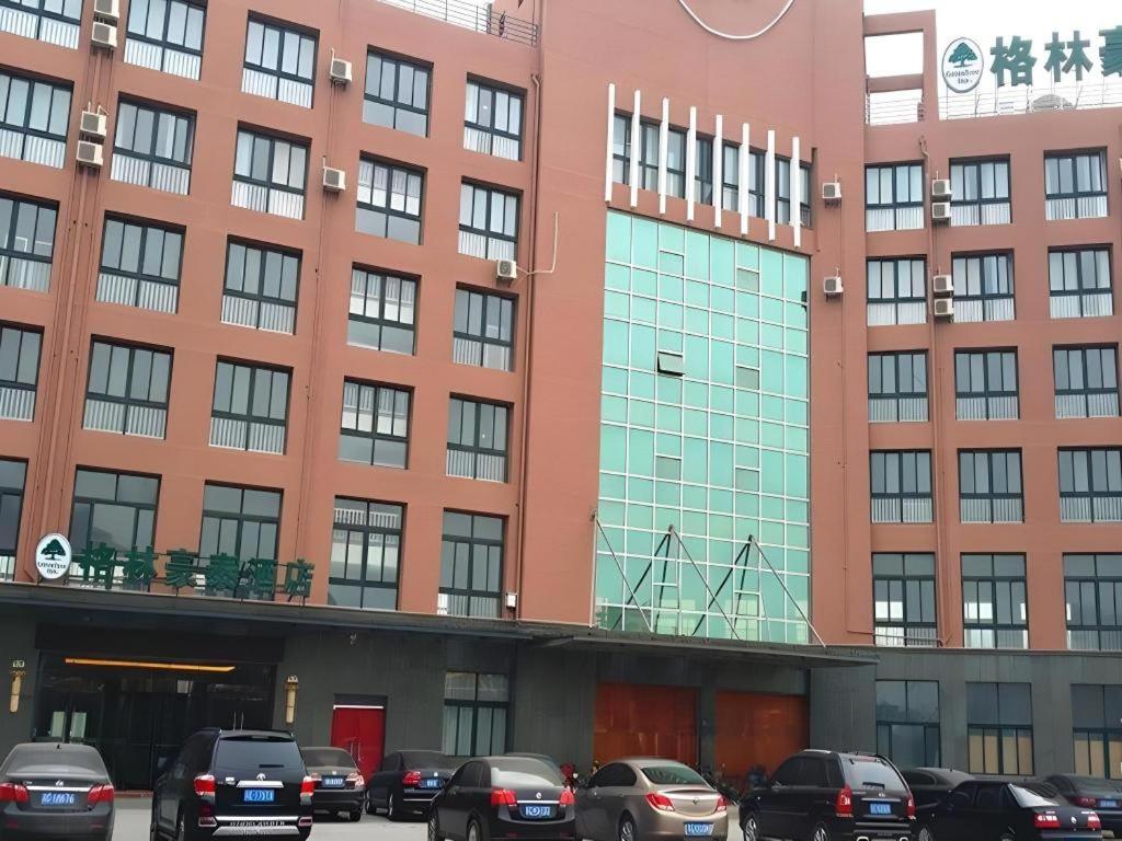 徐州GreenTree Inn Xuzhou High Speed Railway Zhangqian Square Business Hotel的一座大楼，前面停满了汽车