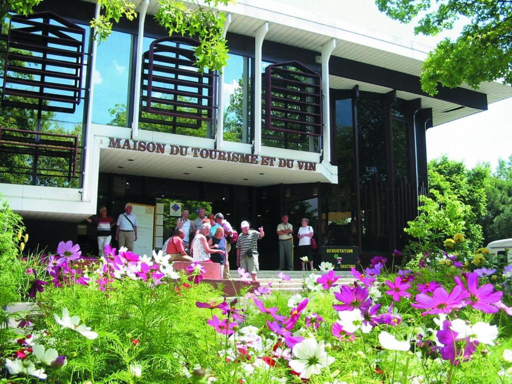 a group of people standing in front of a building with flowers at Le chai de Francky et Lilie in Pauillac