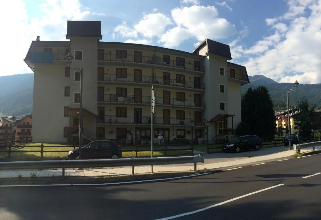 un grande edificio bianco con macchine parcheggiate di fronte di Appartamento Aprica 2.0 ad Aprica