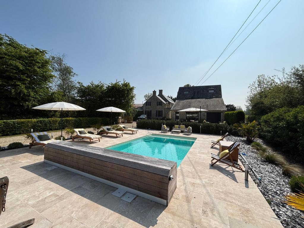 une piscine avec des chaises longues et une maison dans l'établissement La Grange Des Guesdons, à Ellon