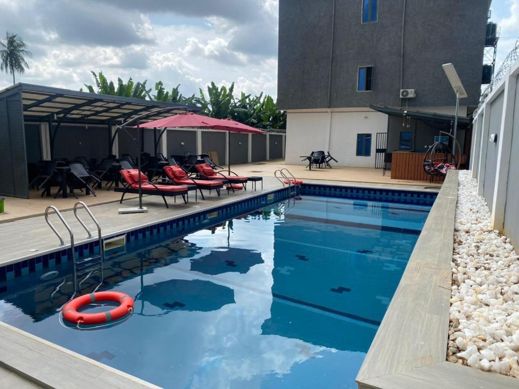 ein Swimmingpool mit Stühlen und Sonnenschirmen neben einem Gebäude in der Unterkunft Victia Suite and Lounge in Ijebu Ode