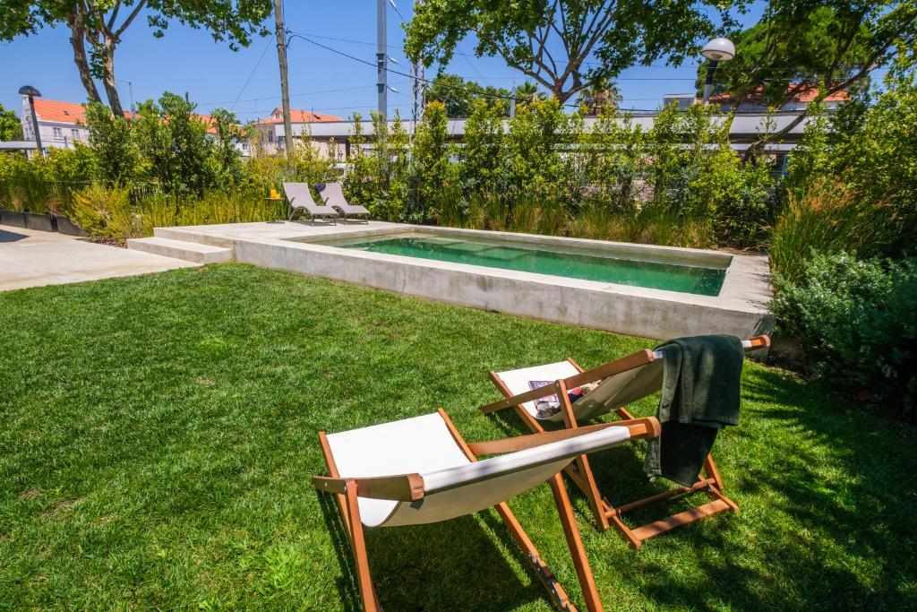 een tuin met twee stoelen en een zwembad bij Chalet Lídia Lodges in Estoril