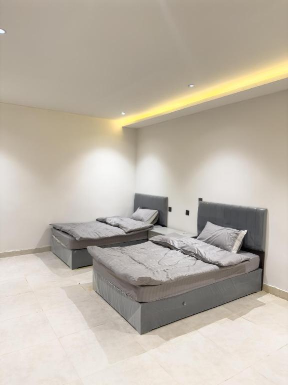 Dos camas en una habitación con paredes blancas. en hotel city, en Al Bad‘