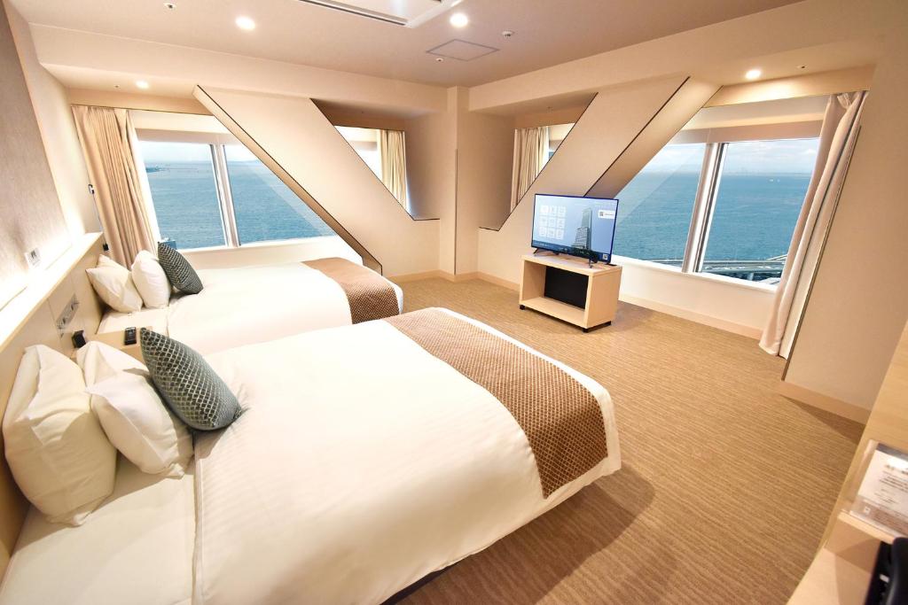 泉佐野Odysis Suites Osaka Airport Hotel的有两张床和一台电视的酒店房间
