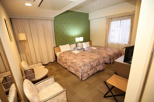 um quarto de hotel com duas camas e uma televisão em Apoa Hotel em Yokkaichi