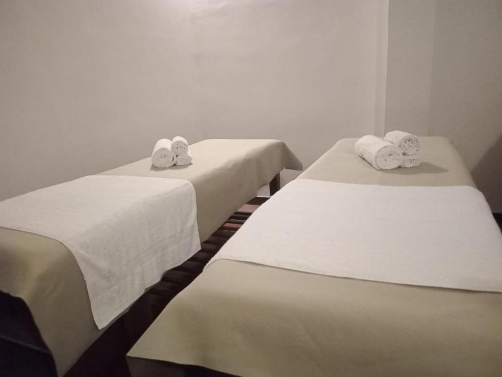 two beds in a room with white sheets and towels at Siddhajeewa Ceylon Herbs in Ella