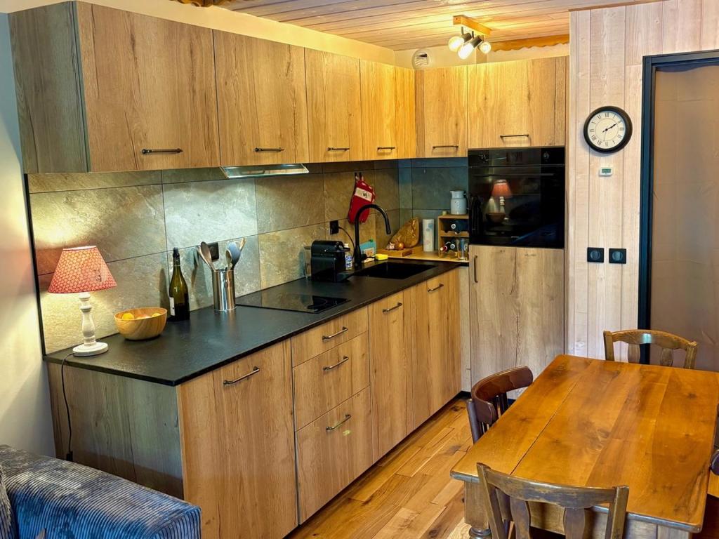 een keuken met houten kasten en een tafel met een klok bij RPP C213 - Charmant appt 4pers-Ski aux pieds in Tignes