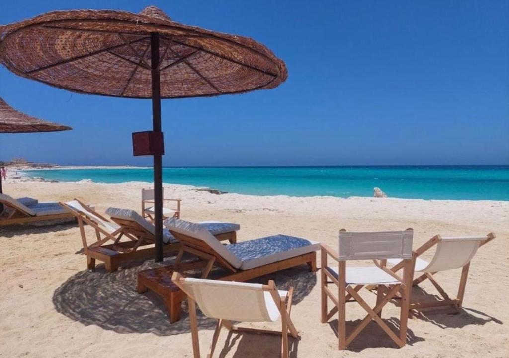 a group of chairs and an umbrella on a beach at Stella villa in El Alamein