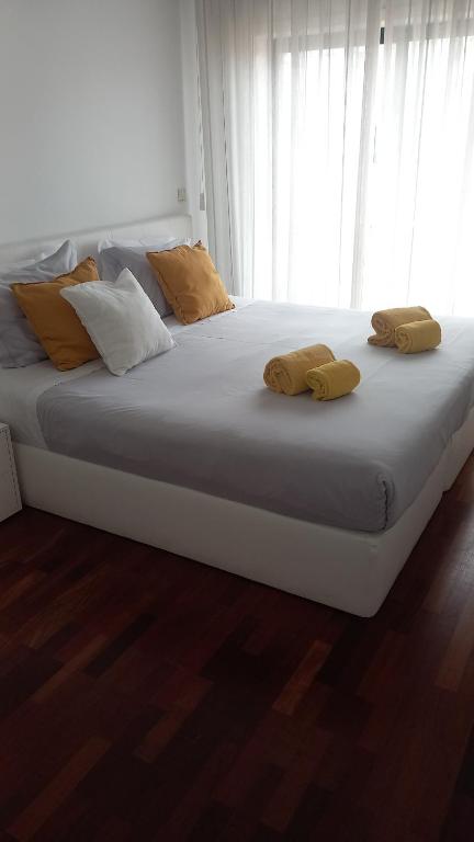 a large white bed with yellow pillows on it at Apartamento Mouzinho de Albuquerque in Matosinhos
