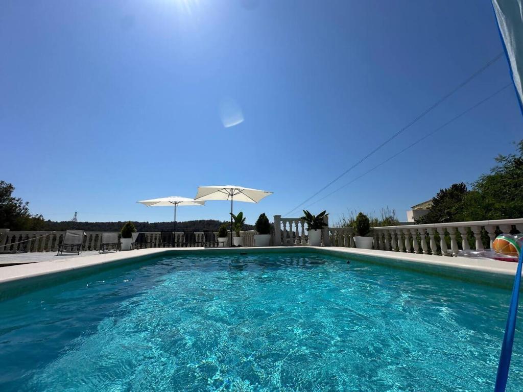 basen z niebieską wodą i parasolem w obiekcie Villa Maja Calpe w mieście Calpe