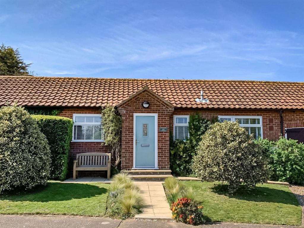 a brick house with a blue door and a bench at September Cottage in Brancaster