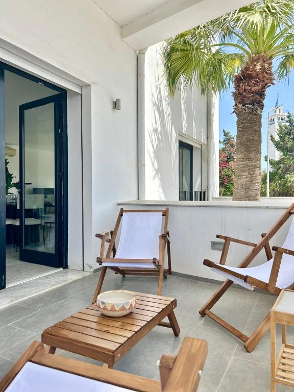 a patio with two chairs and a table and a palm tree at Appartement Casa bloom in Gammarth