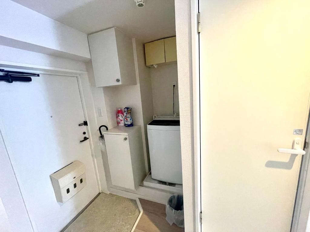 a small bathroom with a toilet and a door at Tokyo West Shinjuku close to Shinjuku Chuo Park in Tokyo