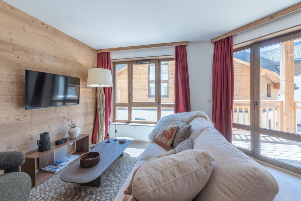 a living room with a couch and a tv at Le Refuge du Pic in L'Alpe-d'Huez