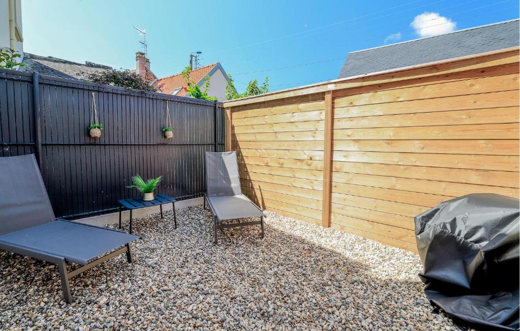 a backyard with two chairs and a fence at Jolie Maison Proche Plage in Le Crotoy