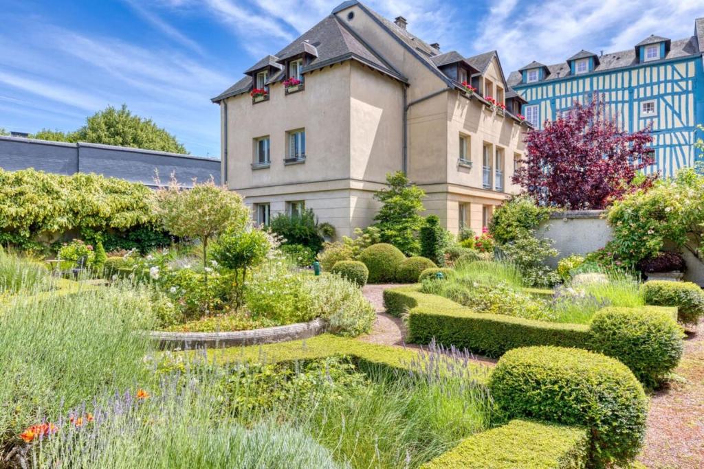 un jardin en face d'un immeuble avec des buissons dans l'établissement Rafael F2 dans hôtel particulier, à Rouen