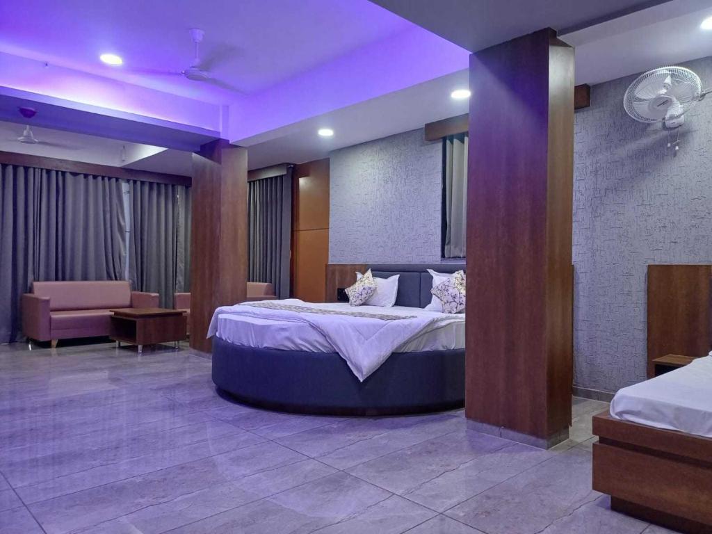 a bedroom with a large bed with purple lighting at Hotel O Heritage Inn in Mehsāna