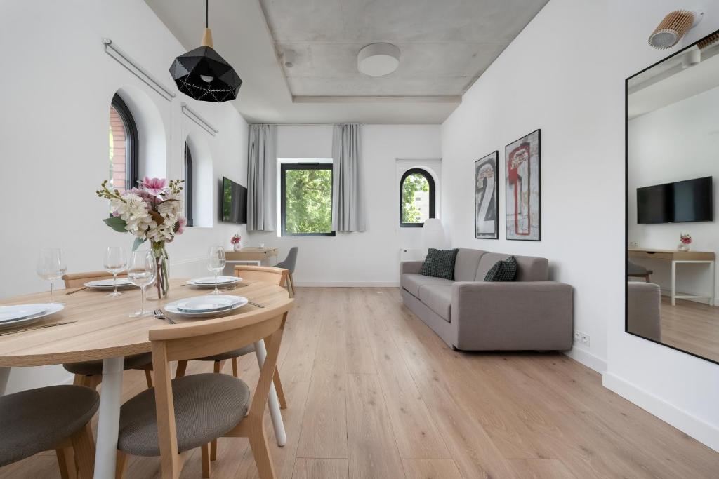 una sala de estar con una mesa y un sofá en PIEKARNIA Żywa Kultura Atmospheric Apartments in Wrocław by Noclegi Renters, en Wroclaw