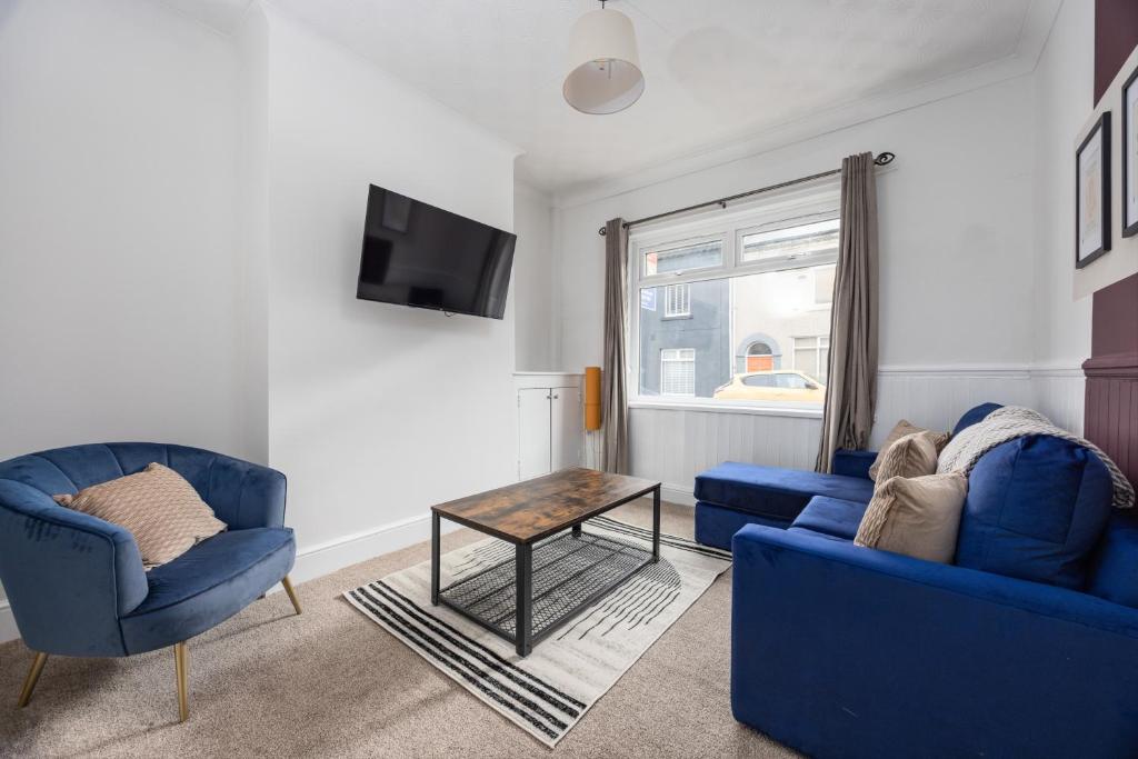 ein Wohnzimmer mit 2 blauen Stühlen und einem Tisch in der Unterkunft Charming 3-BR Home Near Historic Town Centre in Bishop Auckland