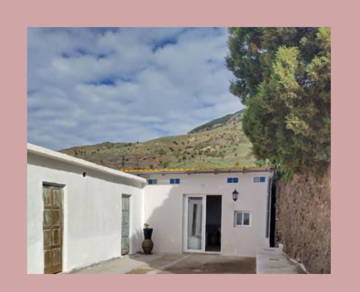 a white building with a mountain in the background at Casa Edelmira Apartment in Vallehermoso