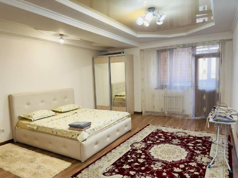 a bedroom with a bed and a rug at Микрорайон Джал in Bishkek