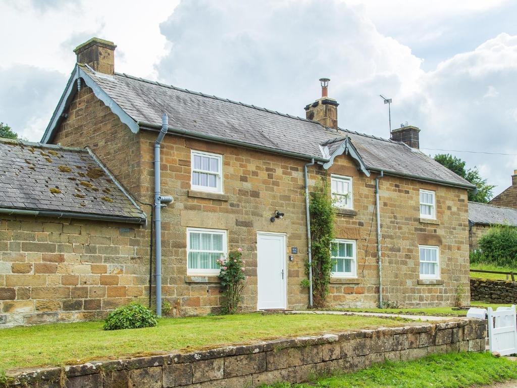 Rose Cottage, Kepwick Village with Hot Tub - Rural Location في Kepwick: منزل من الطوب القديم مع باب أبيض
