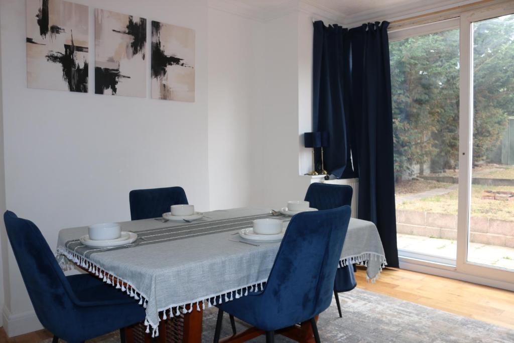 a dining room with a table and blue chairs at 3-Bedroom House, with free parking in Luton