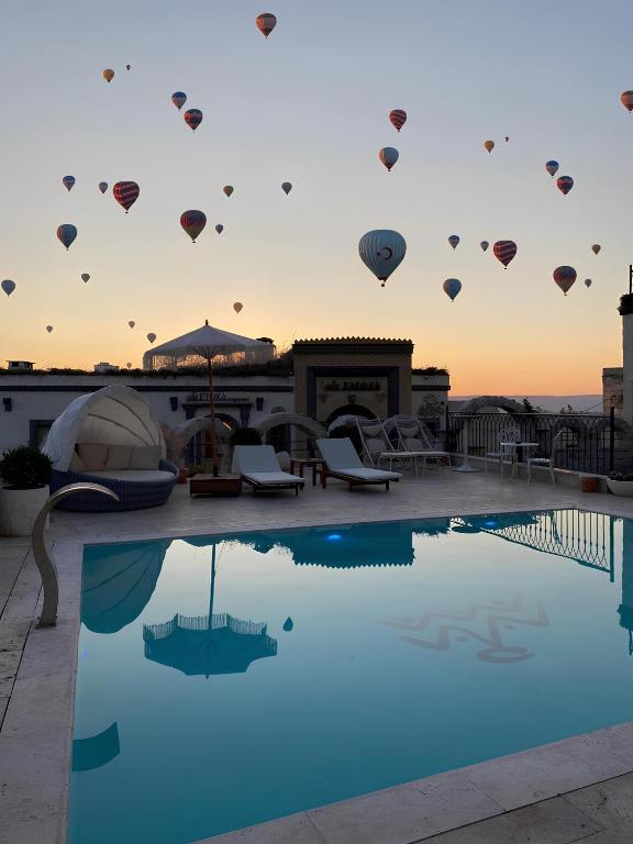 a pool with hot air balloons in the sky at Zafora Cave Suites Hotel Cappadocia in Uçhisar