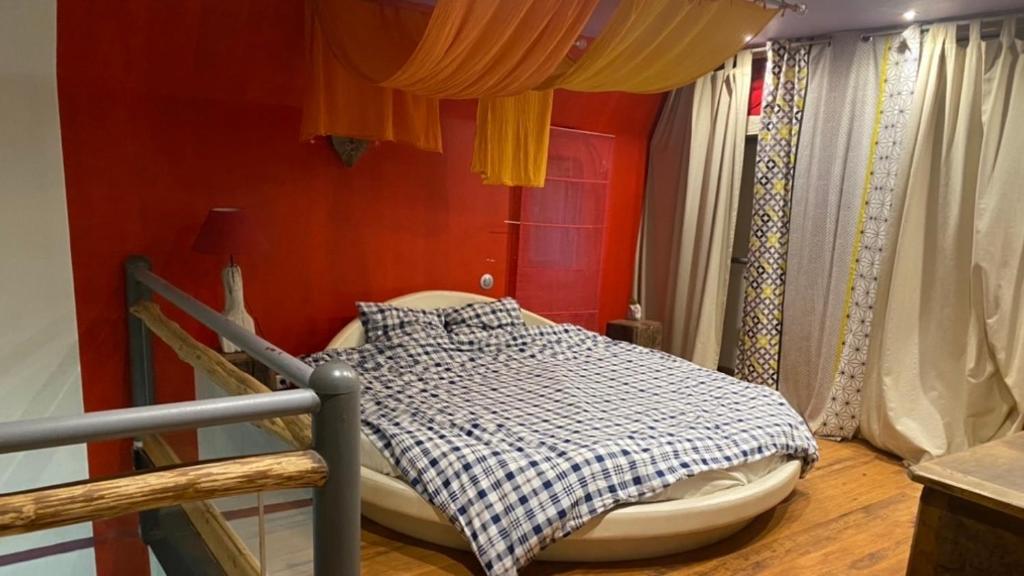 a bed in a room with red walls and curtains at La chanvrière in Beaulieu-sur-Loire