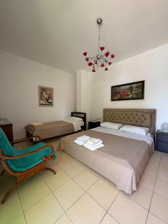 a bedroom with a bed and a chair and a chandelier at Valeon Apartment Three in Sarandë
