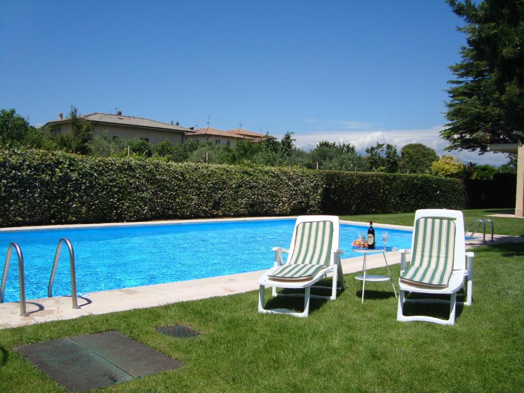two chairs and a table next to a swimming pool at Casa Sole Appartement con terrazzo in Bardolino