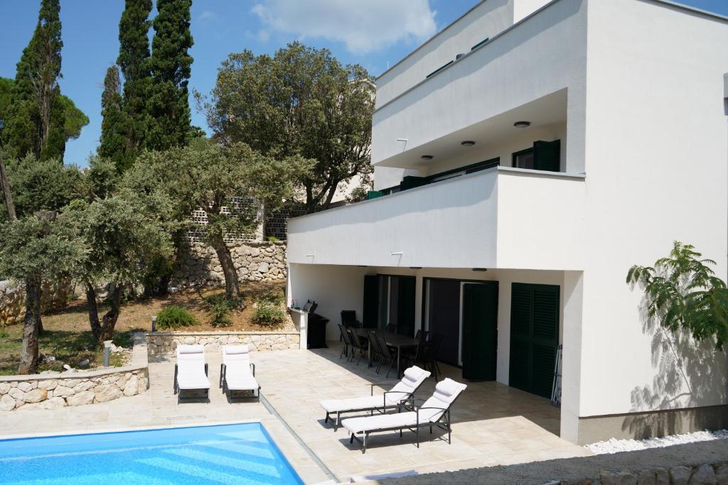 una casa blanca con una piscina delante de ella en Villa Novak, en Rab