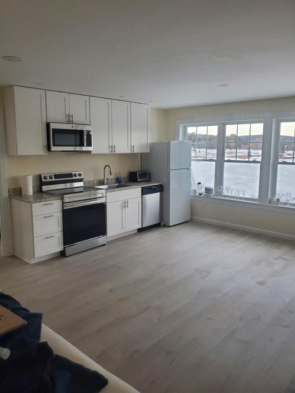 a kitchen with white appliances and a large window at Acadia Horizon Cottage in Southwest Harbor