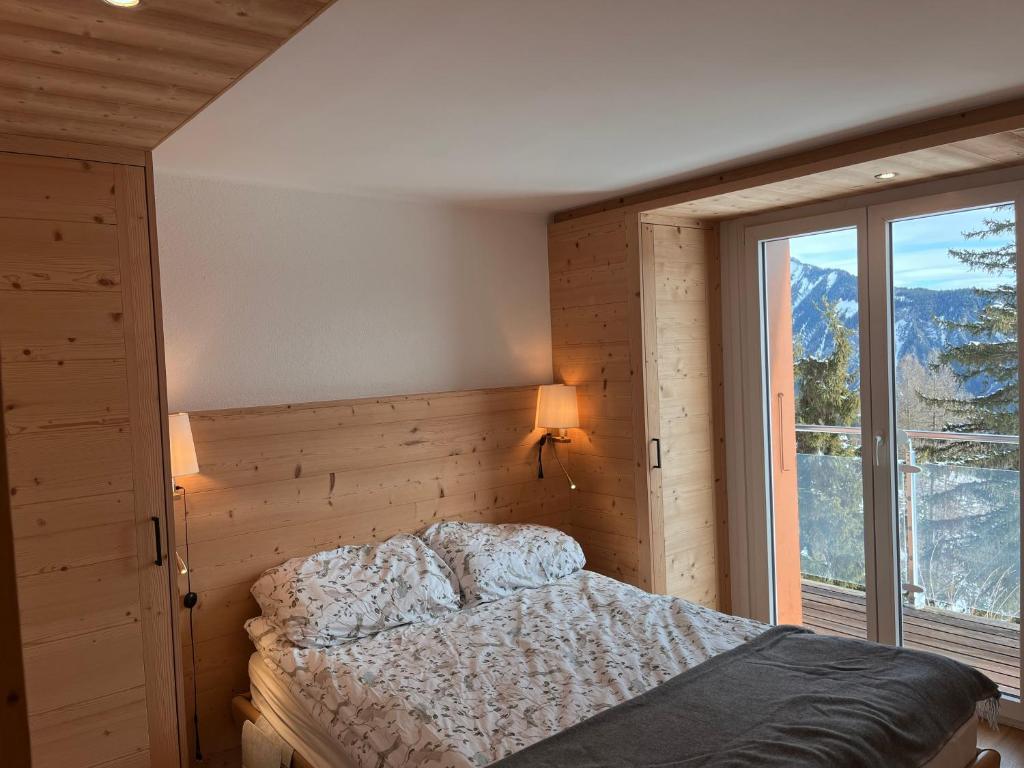ContheyにあるChalet les jougesのベッドと大きな窓のある寝室