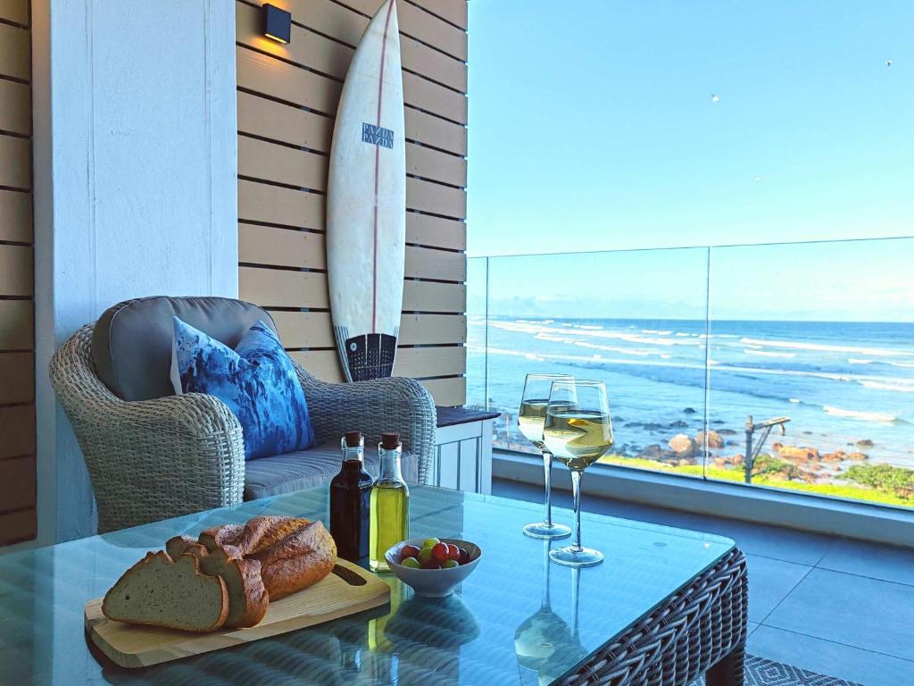 a table with a glass of wine and a surfboard at Wavescapes Hang Ten Stay in Cape Town