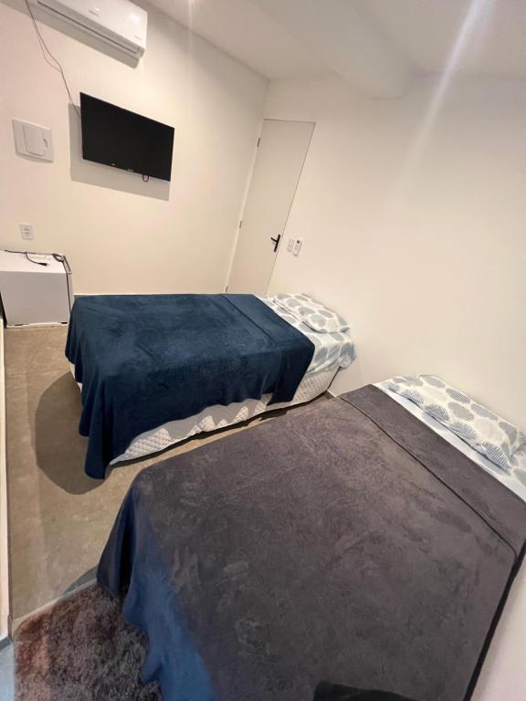 two beds in a room with a tv on the wall at Manaira Suite 03 in João Pessoa