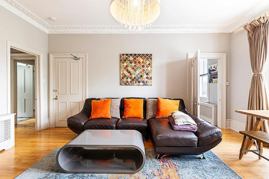 a living room with a leather couch and orange pillows at Super Chic 1-Bedroom Urban Hideaway in Twickenham